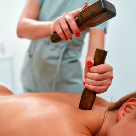 massage therapist during a traditional Thai massage tok-sen. Oriental alternative medicine with wooden tools. Body care and SPA in santaigo de compostela